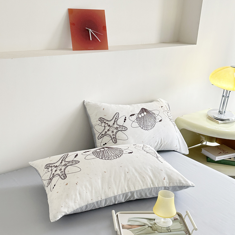 two pillows are featuring sketched illustrations of marine life, such as starfish and seashell 