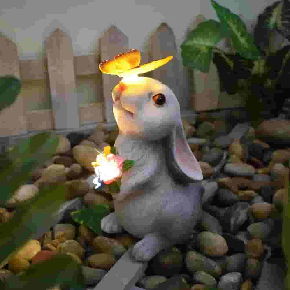 Solar rabbit garden statue with glowing butterfly on nose and LED flowers, IP65 waterproof resin bunny yard decor.
