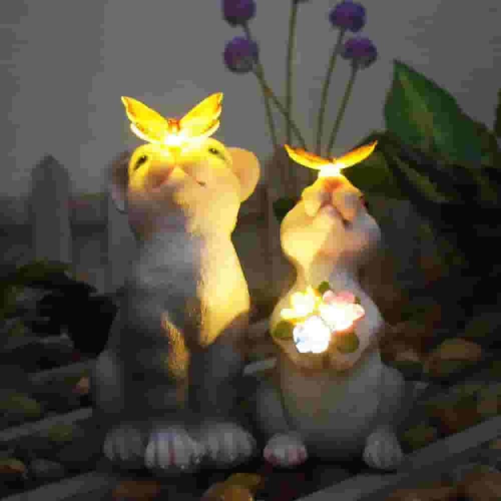 Solar rabbit garden statue with glowing butterfly on nose and LED flowers, IP65 waterproof resin bunny yard decor.