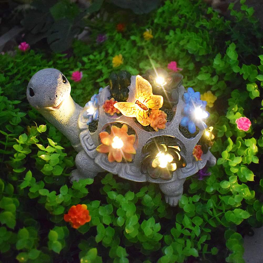 Solar turtle statue with glowing butterfly and colorful LED flowers on shell, water-resistant garden ornament for flower beds.