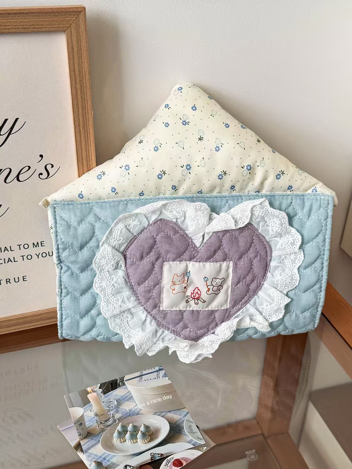Close-up of lace heart embroidered hanging tissue holder, quilted fabric tissue box cover for aesthetic room decor.