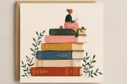 Cozy girl reading on a stack of colorful books - book lover birthday card. 