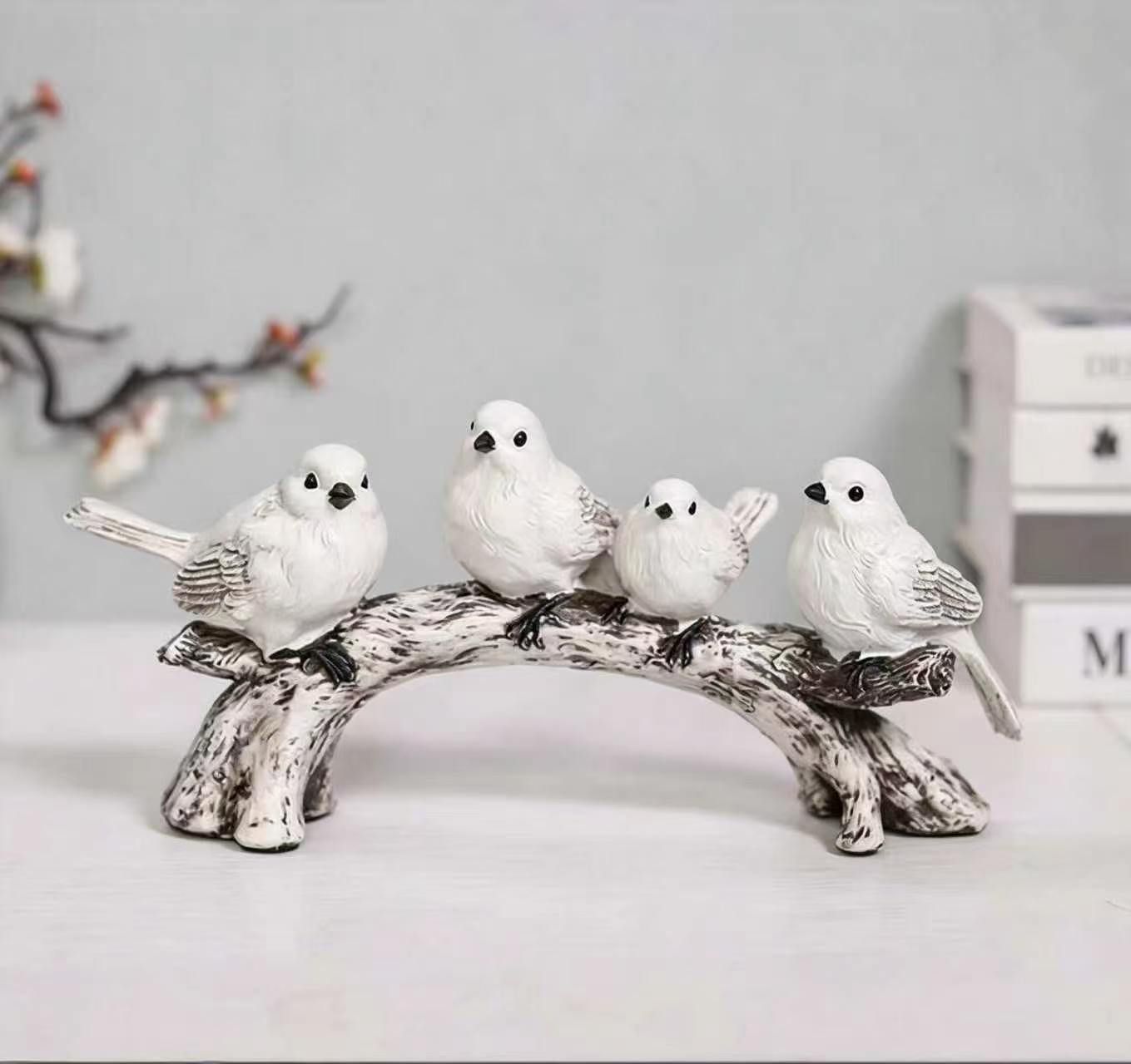 Four white bird figurines arranged along an arched branch