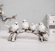 Four white bird figurines arranged along an arched branch