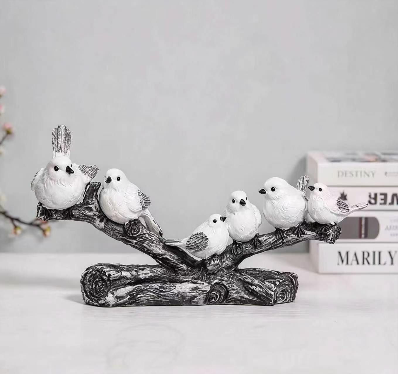 Six white birds perched on a long sculpted branch