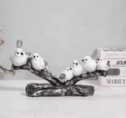 Six white birds perched on a long sculpted branch